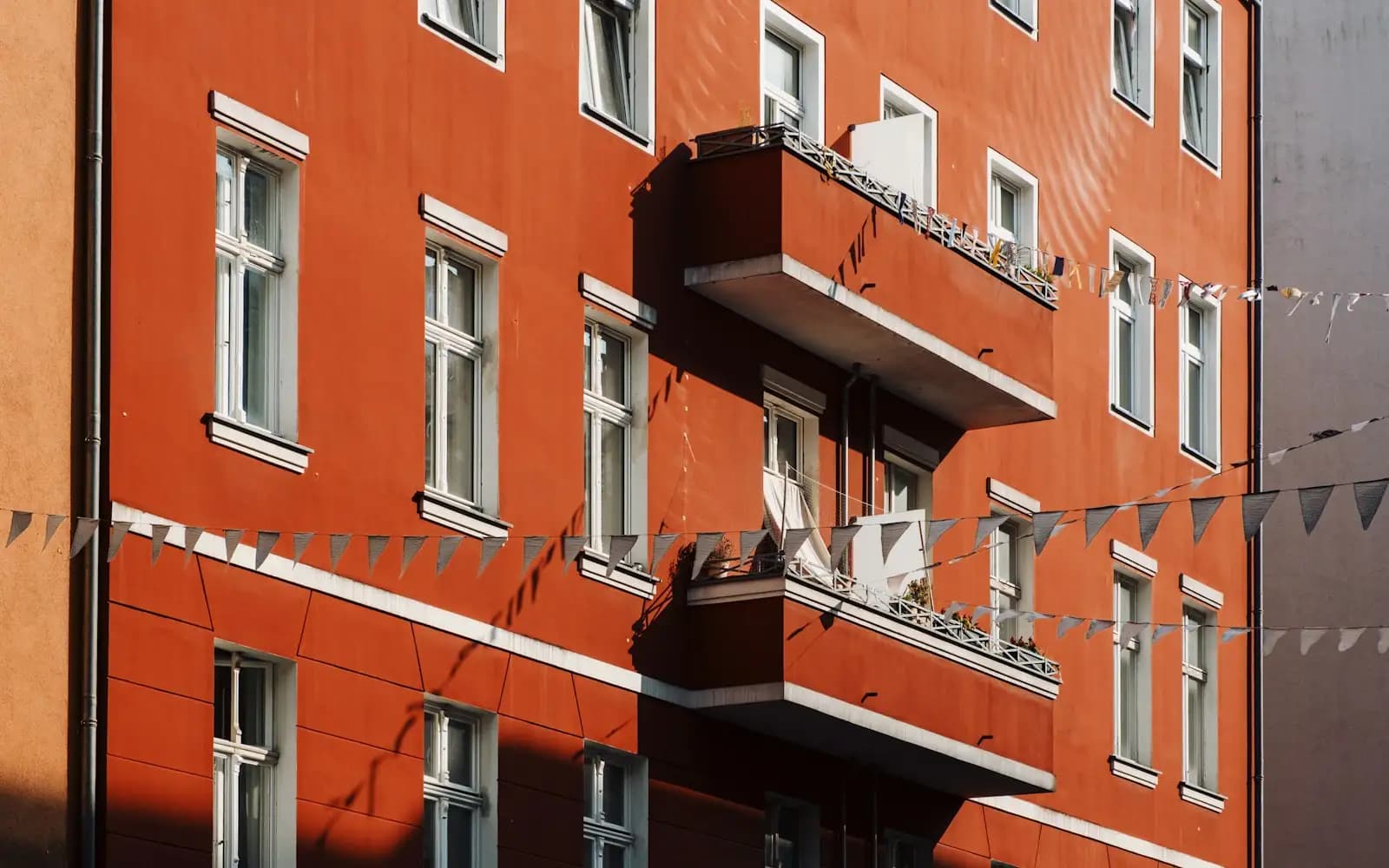 Beispielbild: rote Altbaufassade mit weißen Fenstern und Balkon